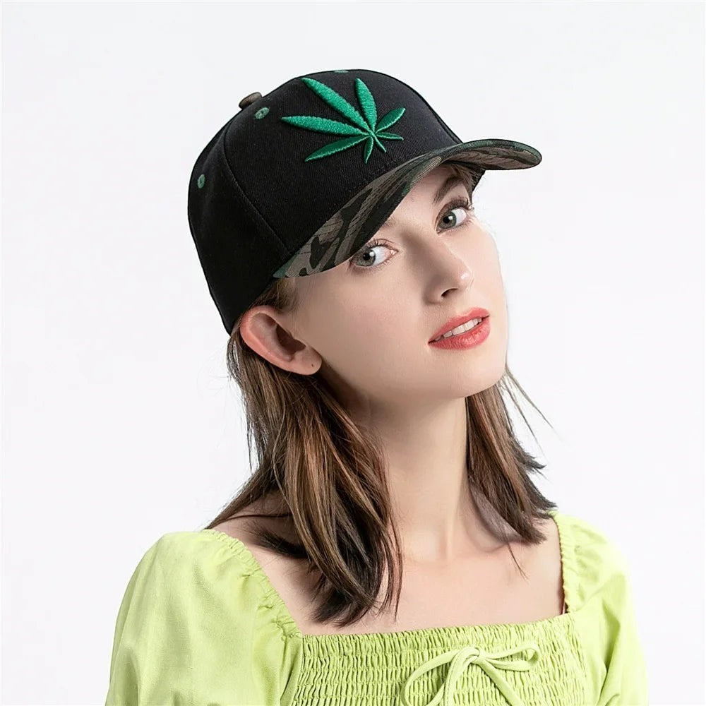 AKJ Fashion black polyester baseball cap with green cannabis leaf embroidery and camouflage brim. Adjustable strap for unisex adult wear.