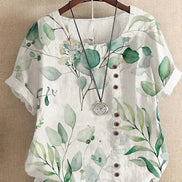 AKJ Fashion blouse blanche à imprimé feuillage vert, col rond, boutonnage décalé, manches courtes retroussées. Tissu effet lin.