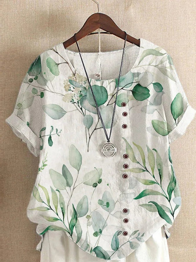 AKJ Fashion blouse blanche à imprimé feuillage vert, col rond, boutonnage décalé, manches courtes retroussées. Tissu effet lin.