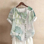 AKJ Fashion blouse verte à imprimé feuilles et fleurs, col rond, manches courtes retroussées, boutonnage décalé, effet lin.