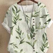 AKJ Fashion blouse verte à imprimé feuilles et fleurs, col rond, manches courtes retroussées, boutonnage décalé.