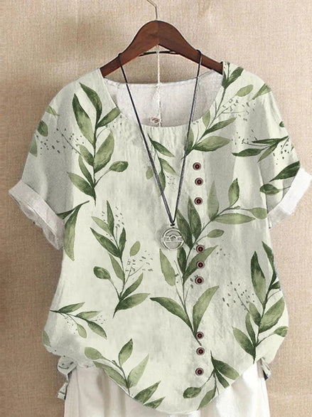 AKJ Fashion blouse verte à imprimé feuilles et fleurs, col rond, manches courtes retroussées, boutonnage décalé.