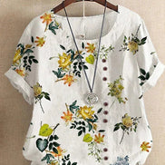 AKJ Fashion blouse blanche à imprimé floral jaune et violet, col rond, manches courtes retroussées, boutonnage décalé.