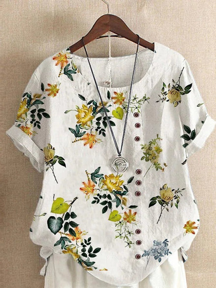 AKJ Fashion blouse blanche à imprimé floral jaune et violet, col rond, manches courtes retroussées, boutonnage décalé.