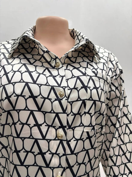 Chemise AKJ Fashion en satin écru et noir, col pointu, boutons dorés, imprimé graphique, coupe droite.