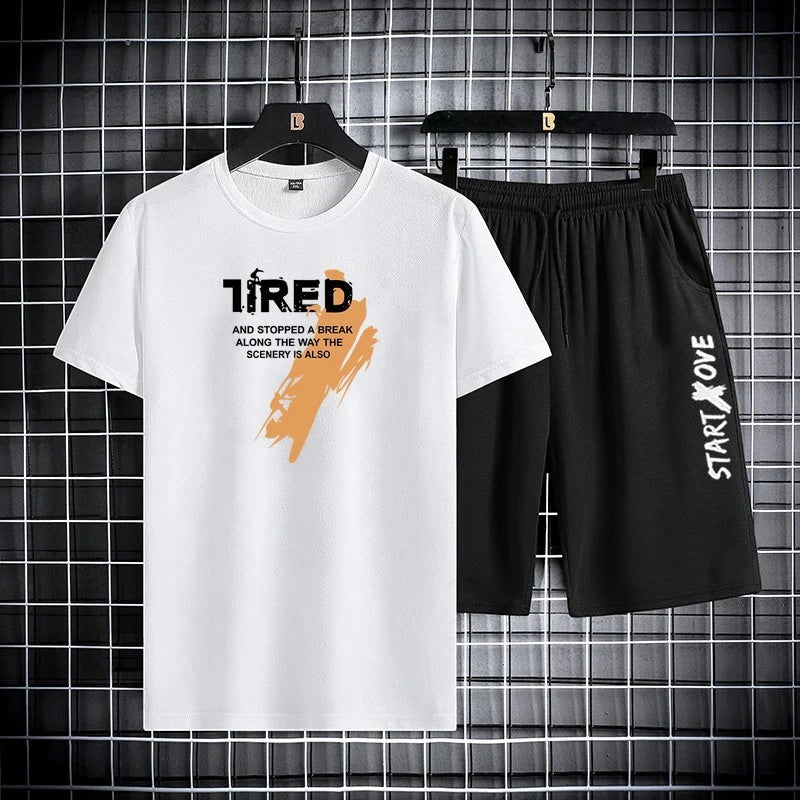 AKJ Fashion white t-shirt with black graphic text and orange brush stroke, paired with black athletic shorts with white text.