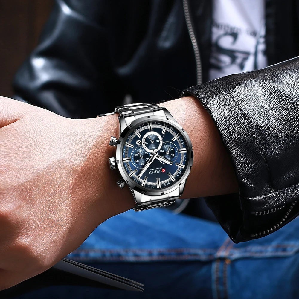 Montre AKJ Fashion CURREN argent, boîtier rond, bracelet acier inoxydable, cadran bleu avec aiguilles lumineuses et date.