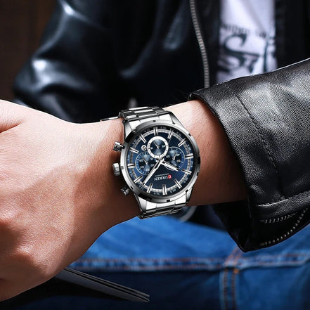 Montre AKJ Fashion CURREN argent, boîtier rond, bracelet acier inoxydable, cadran bleu avec aiguilles lumineuses et date.
