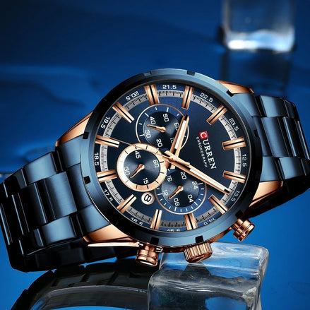 Montre AKJ Fashion CURREN chronographe homme, boîtier et bracelet acier argent, cadran bleu avec détails or rose, date automatique, aiguilles lumineuses.