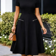 AKJ Fashion robe midi noire évasée à manches courtes, col rond et poches zippées décoratives. Tissu structuré.