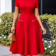 AKJ Fashion robe midi rouge évasée à manches courtes, col rond et poches zippées. Tissu structuré, taille cintrée.